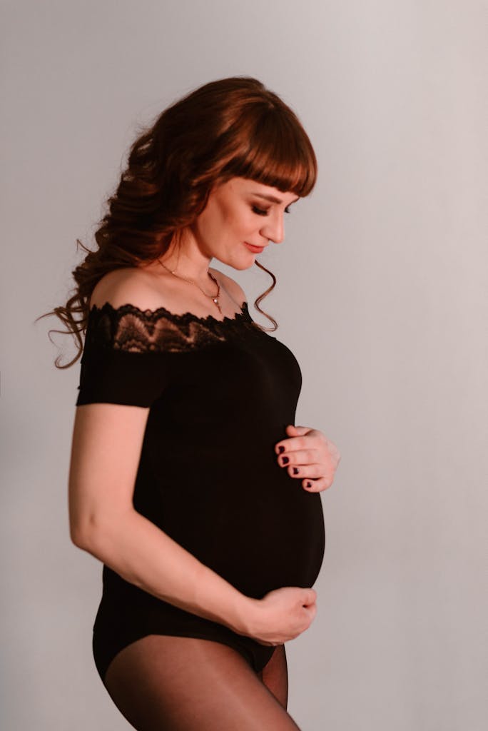 A graceful portrait of a pregnant woman in a black blouse, embracing her baby bump.