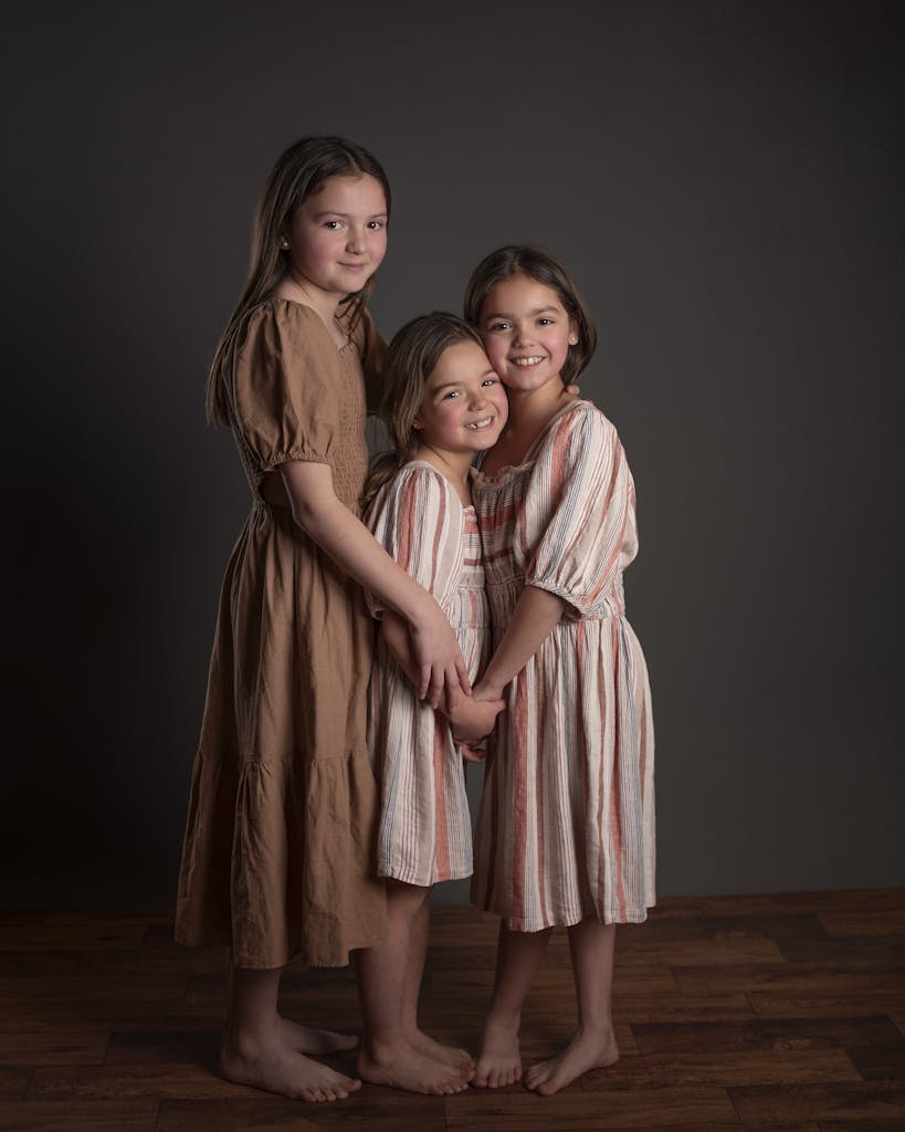 Charming studio portrait capturing the close bond between three young sisters embracing.