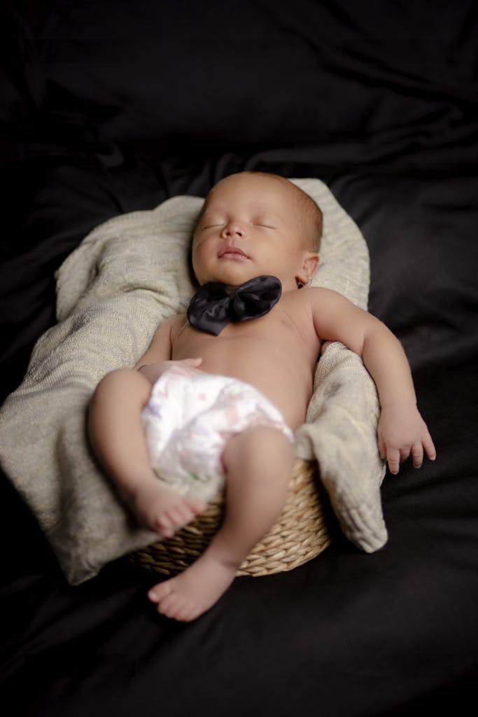 Cute newborn baby peacefully sleeping in a cozy basket, wrapped in a soft blanket.